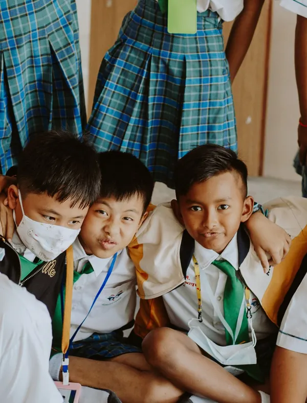 Học sinh tiểu học mặc đồng phục ngồi quây quần trên sàn lớp