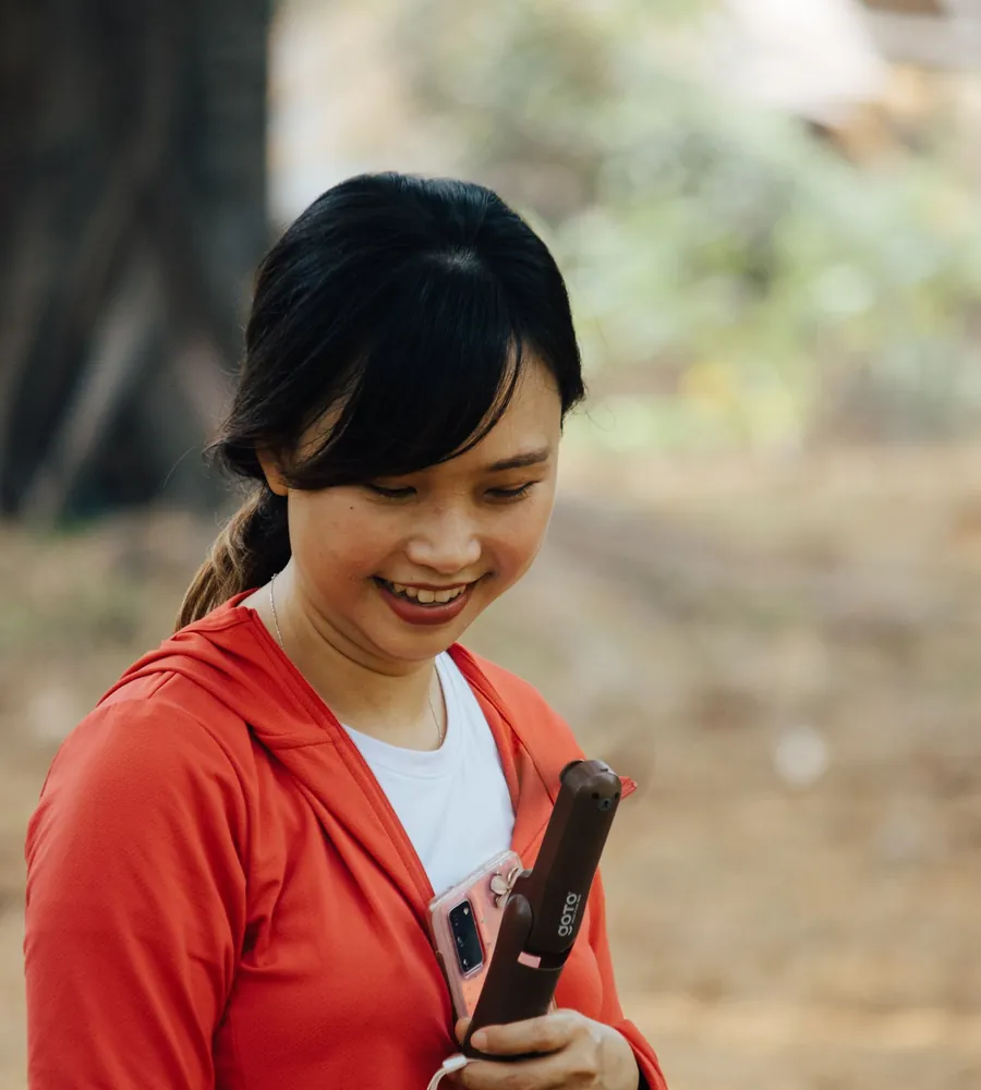 Người phụ nữ mỉm cười nhìn màn hình điện thoại