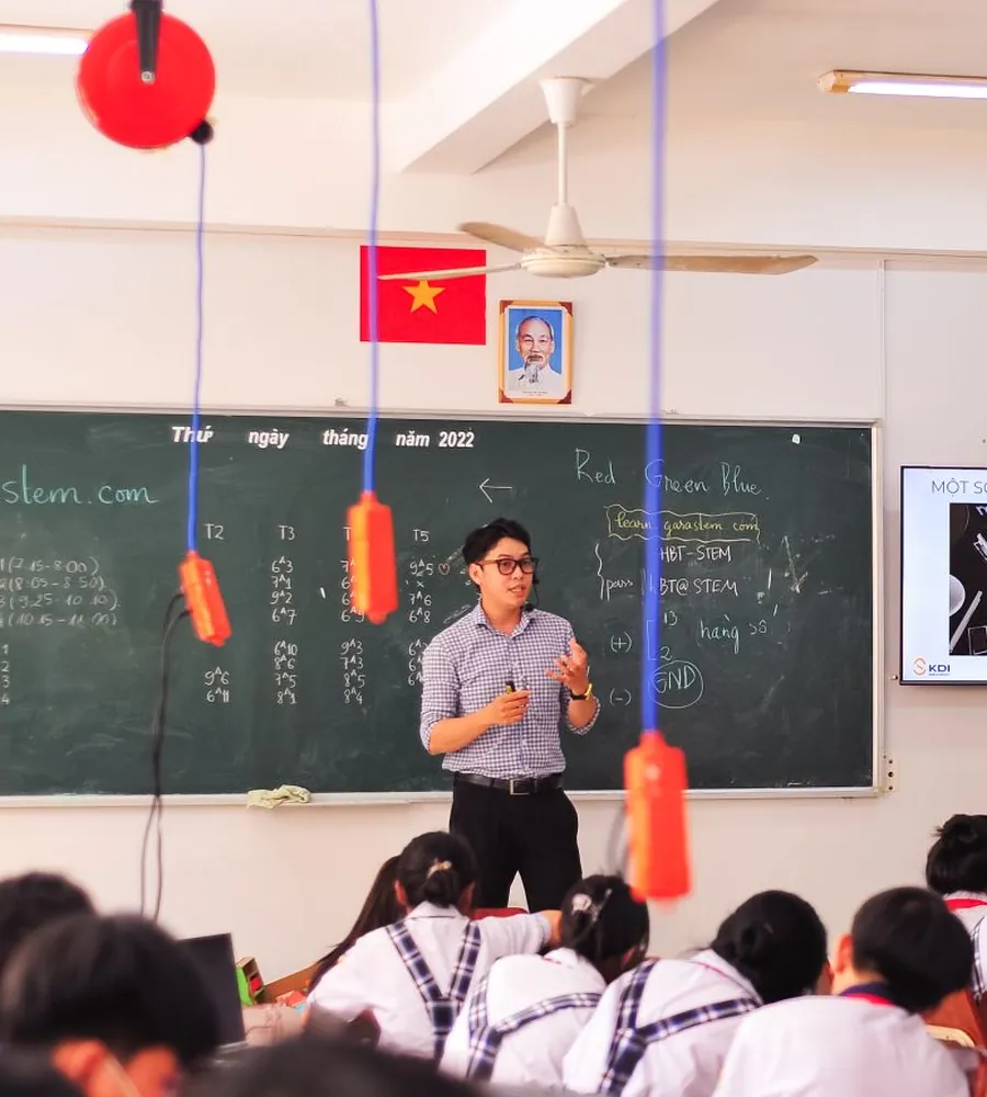 Thầy giáo giảng bài trước lớp học có treo cờ đỏ